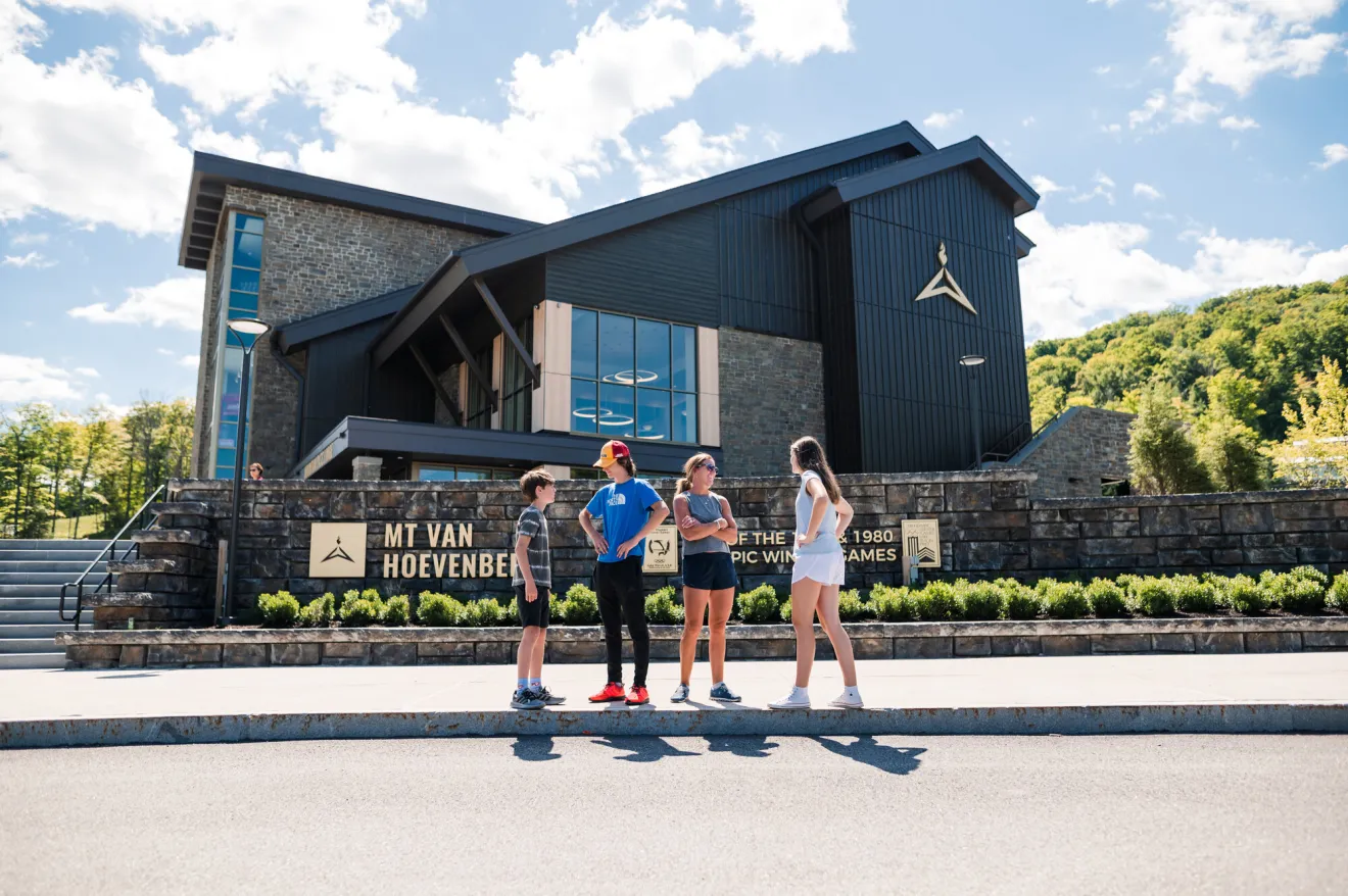 A family stands in front of Mt Van Hoevenberg Lodge. 