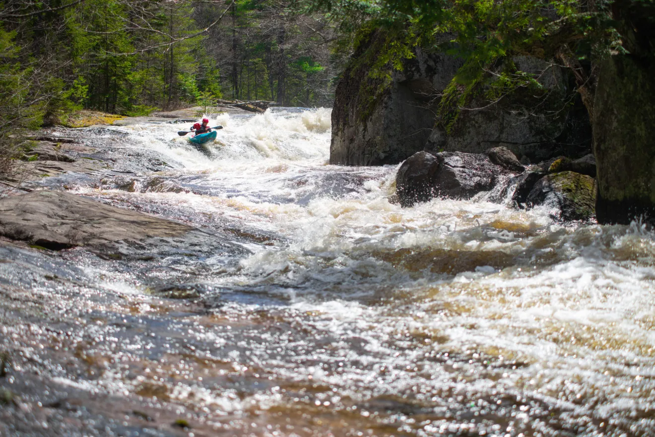 A man kayaks down rushing whitewater. 