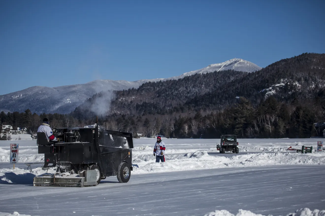 A crew of people use machines to prepare pond hockey rinks on Mirror Lake.