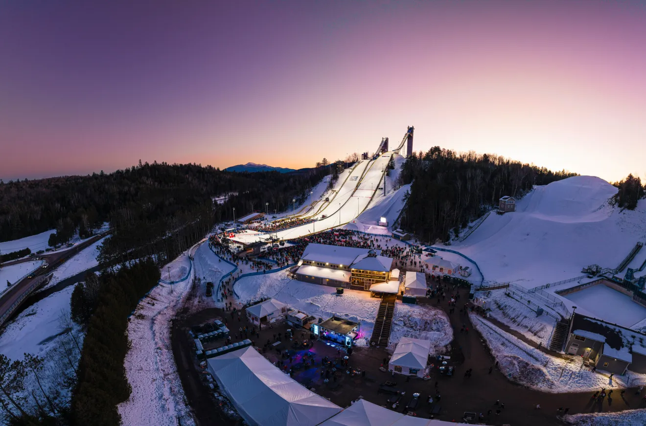 The sun rises over the Olympic Jumping Complex, which is brightly lit for an international competition.