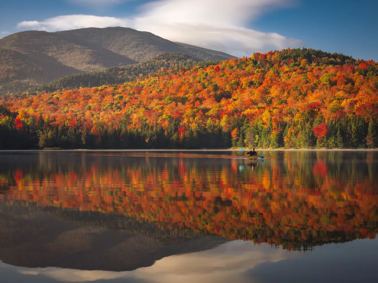 A canoe on a serene lake with beautiful fall foliage