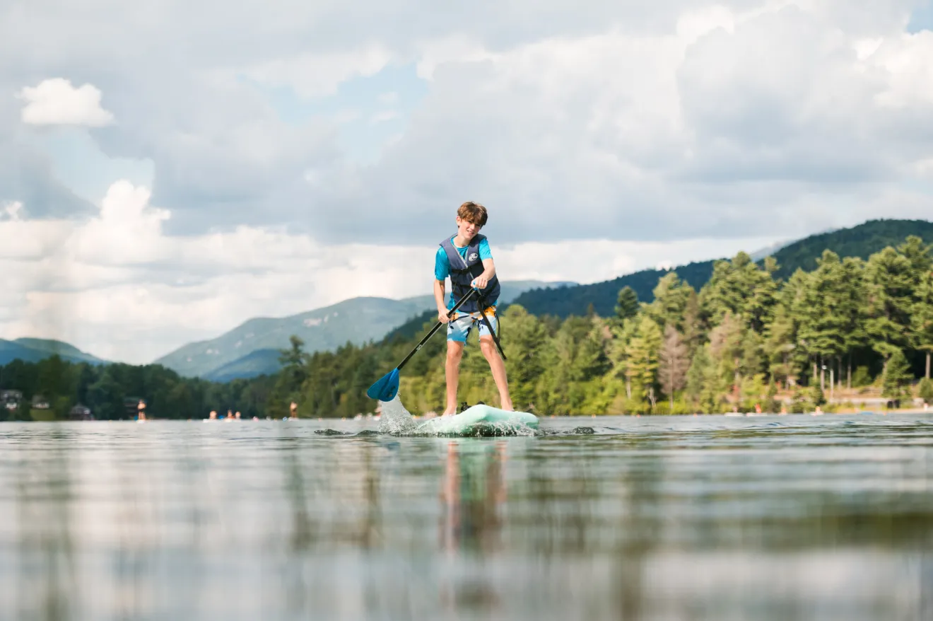 A boy paddling a stand up paddleboard.