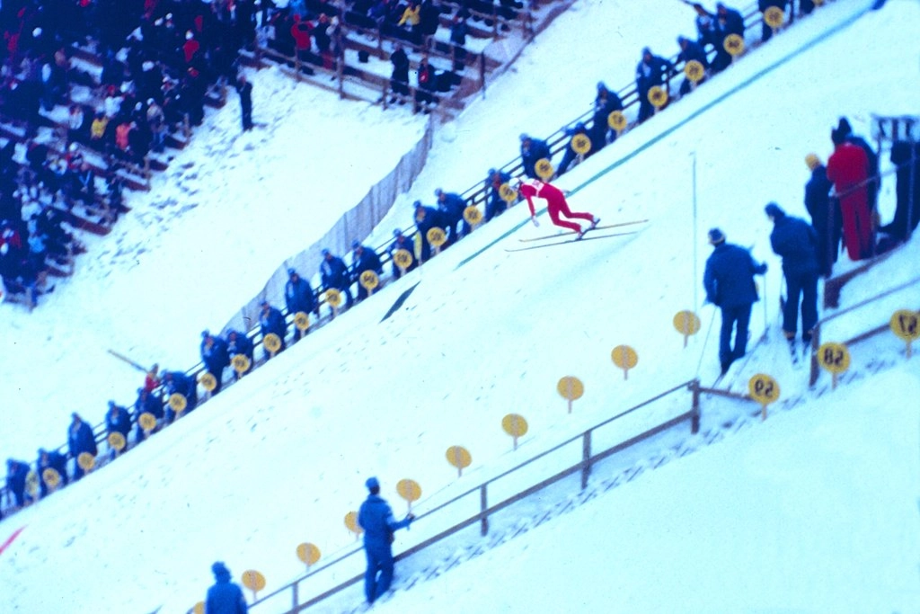 A ski jumper lands on a snowy slope in a vintage color photo from the 1980 Olympic Winter Games.