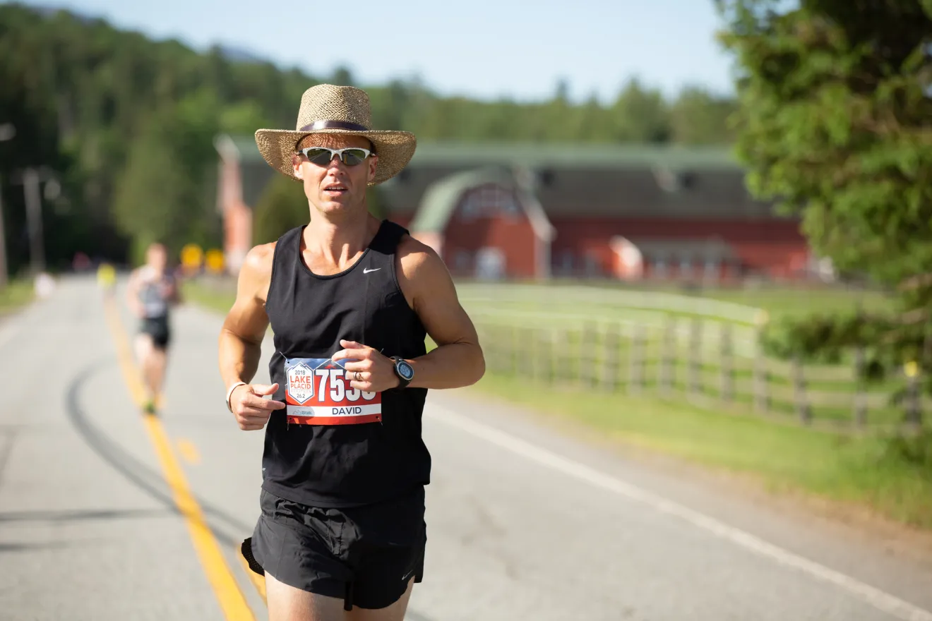 A man in a cowboy hat runs a marathon. 