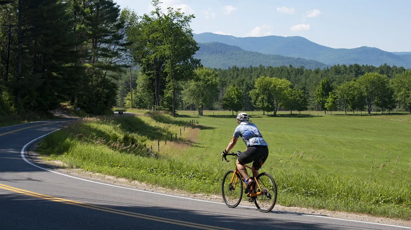 A cyclist rides on a road in the countryside. 