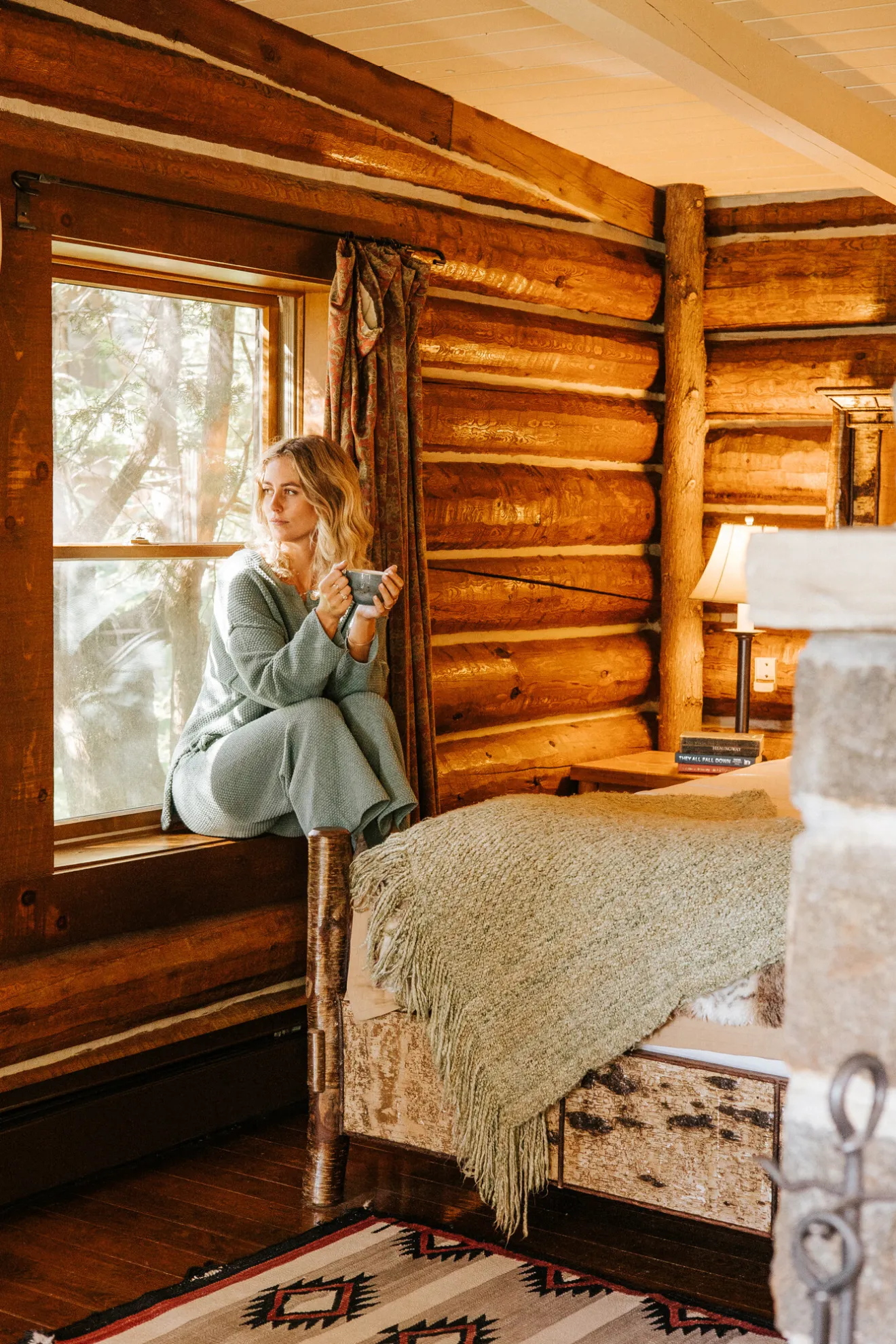 A woman sits on a cabin window sill. 