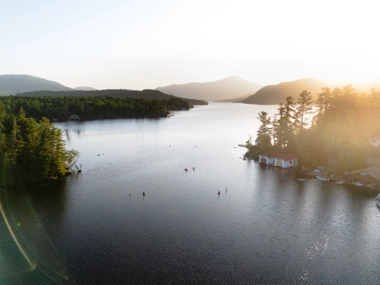 Aerial image of Lake Placid with sun rising over Whiteface Mountain and boats and bouys on the water