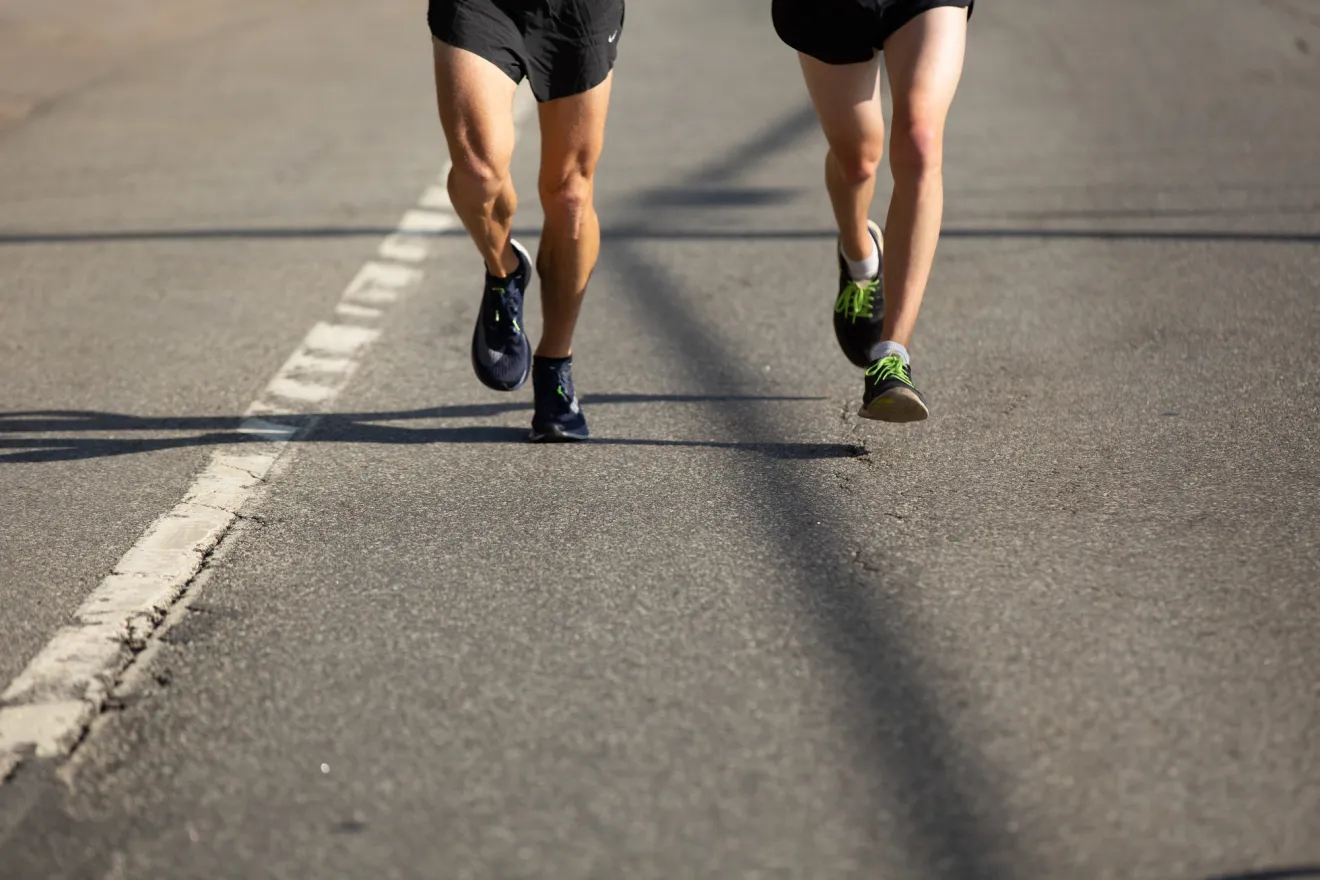 Two people run on a road. 