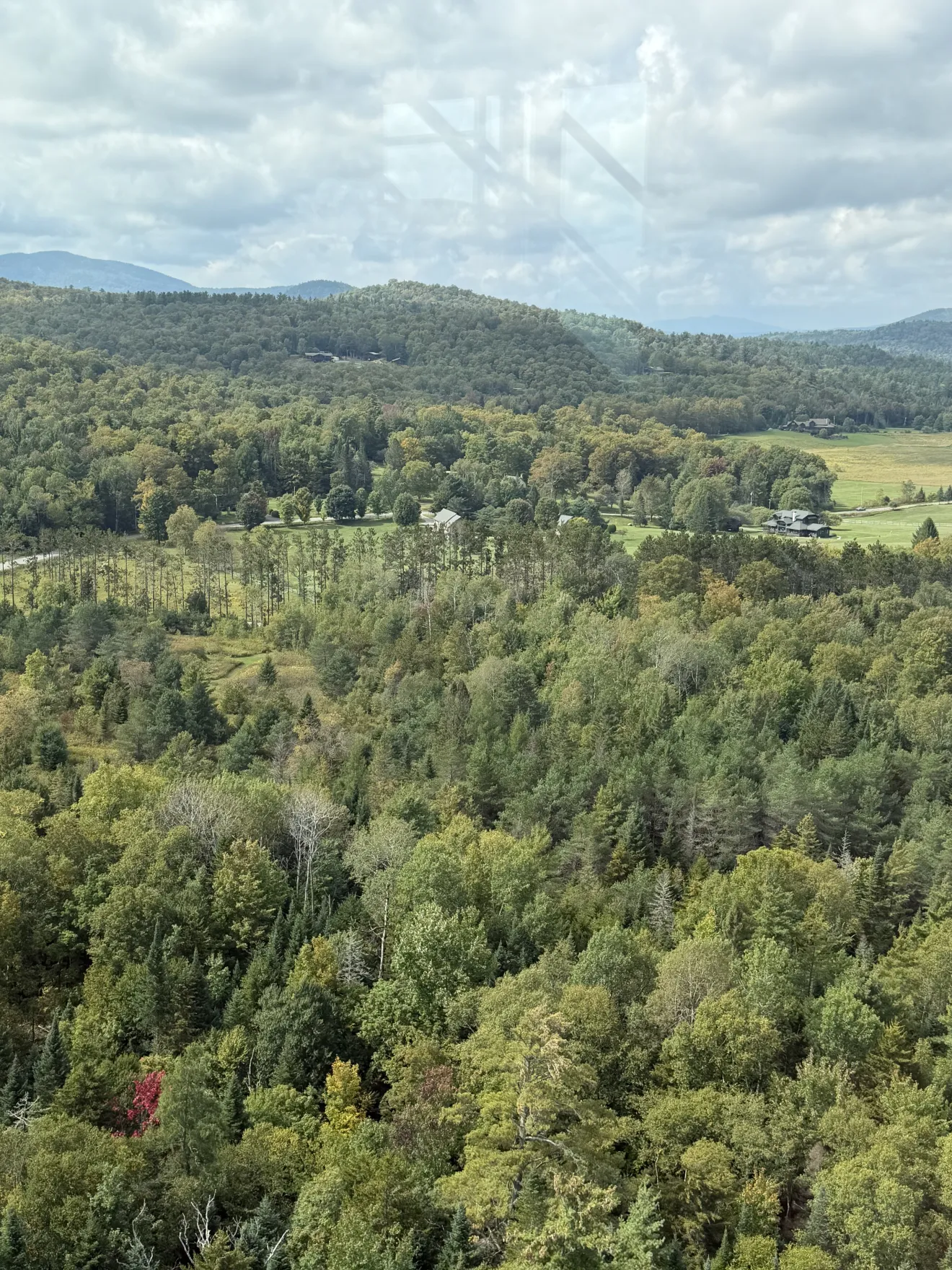 A field and trees in a mountain town beginning to change color for fall.