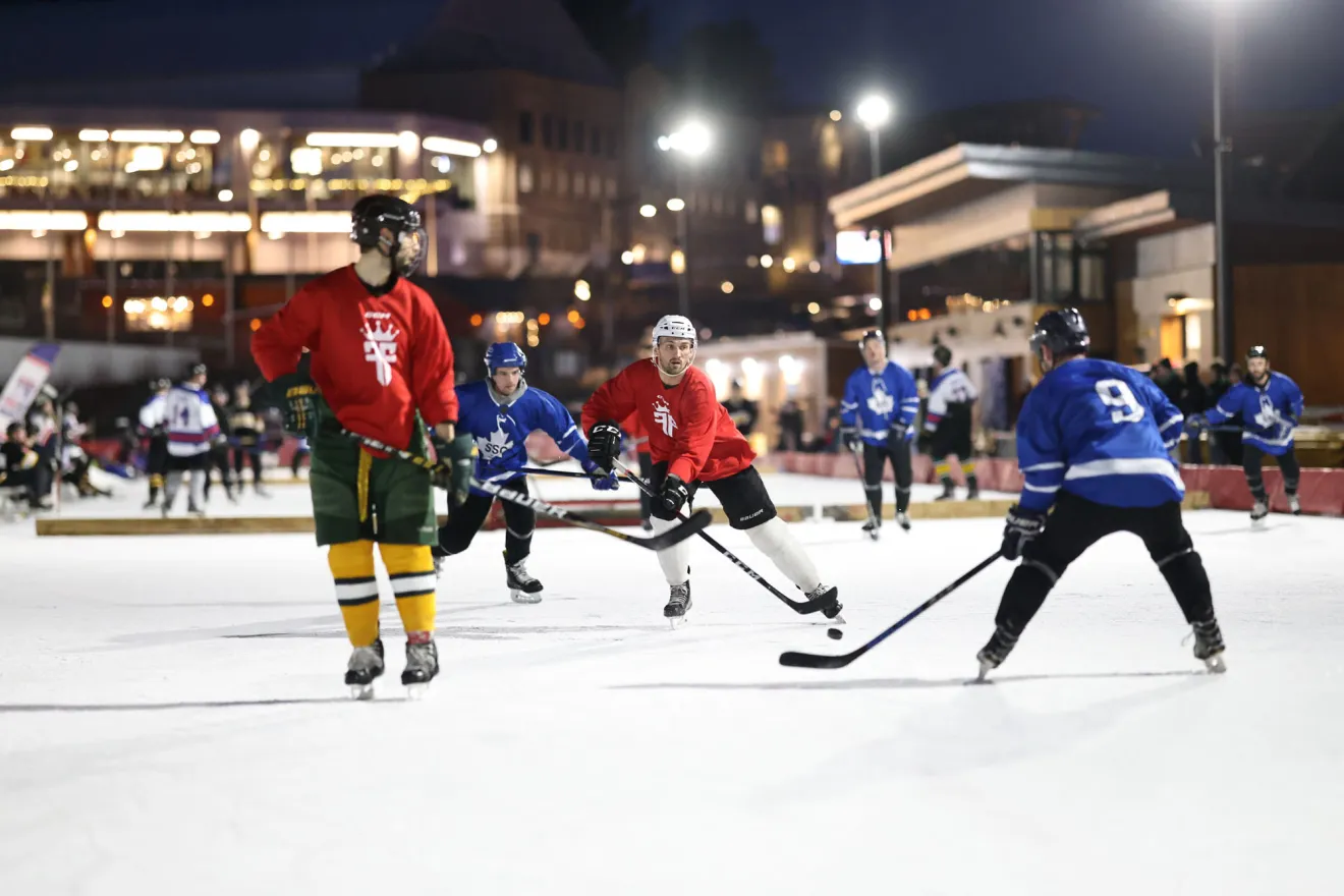 A nighttime outdoor hockey game being played on the Olympic speed skating oval