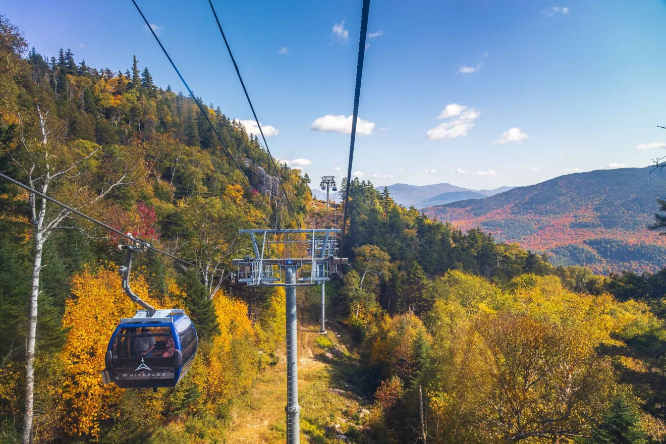 A gondola rises over a mountain during the fall.
