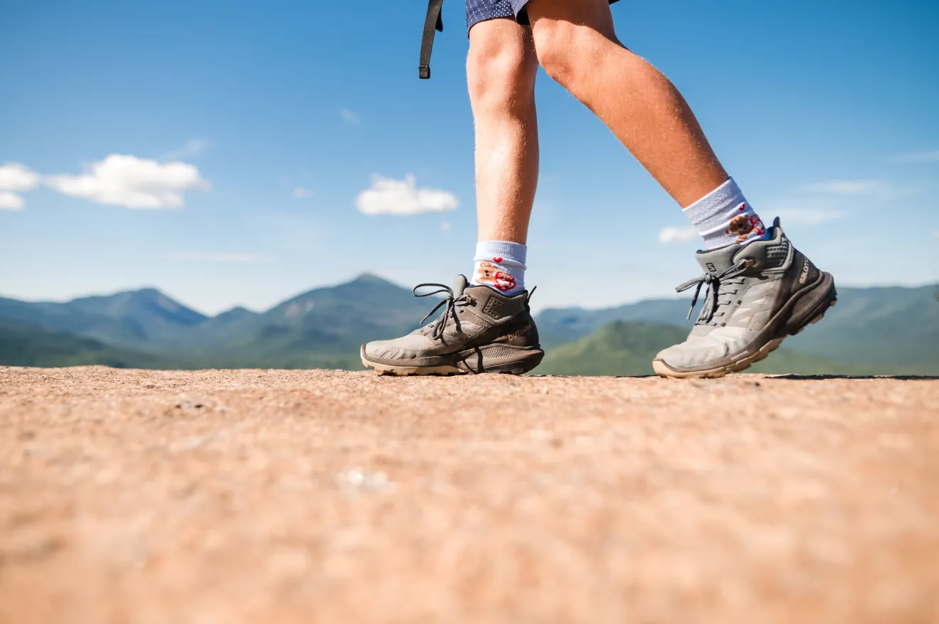 A close up of someones hiking boots while hiking a trail in the summer.