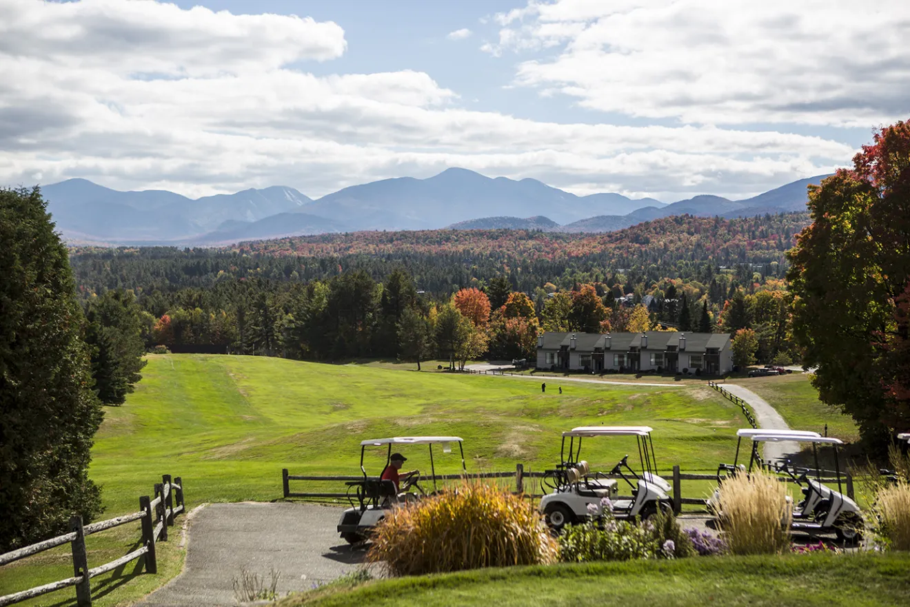 A view over the grassy expanses of a golf course, with mountains in the distance.