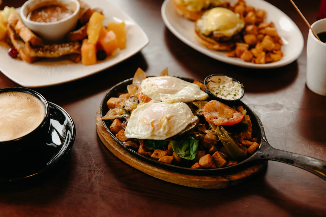 Rösti and other plates of breakfast food on wooden table