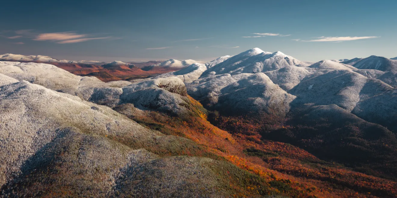 Snow up high and fall foliage down below in the Adirondack Mountains, seen from the sky