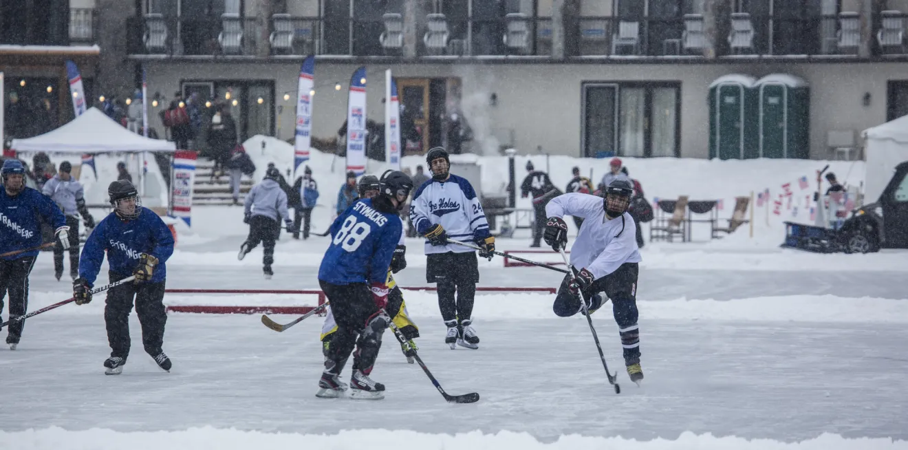 A pond hockey tournament fills several small rinks on a frozen lake.