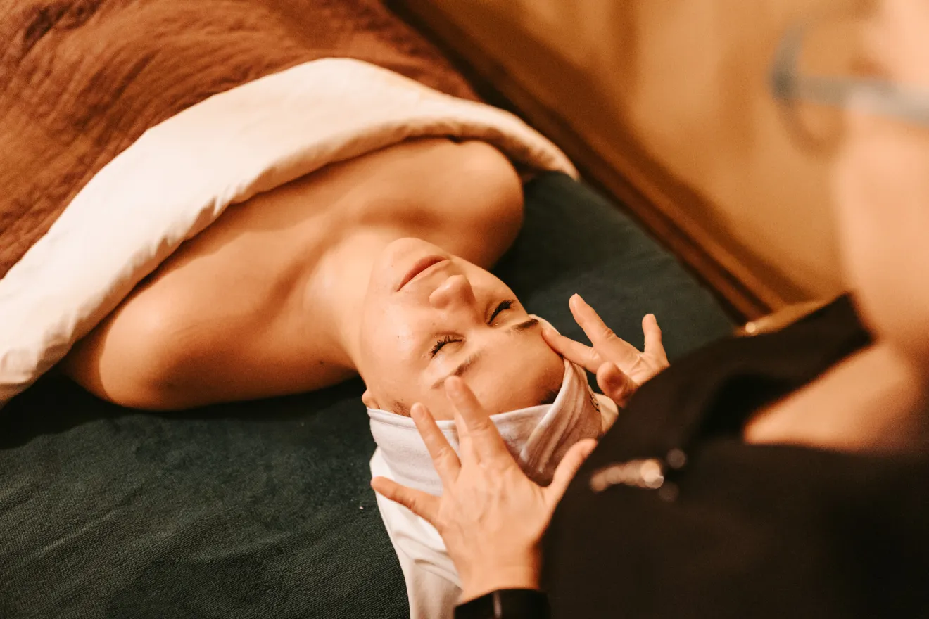 A woman lays down on a table while a spa attendant gives her a massage. 