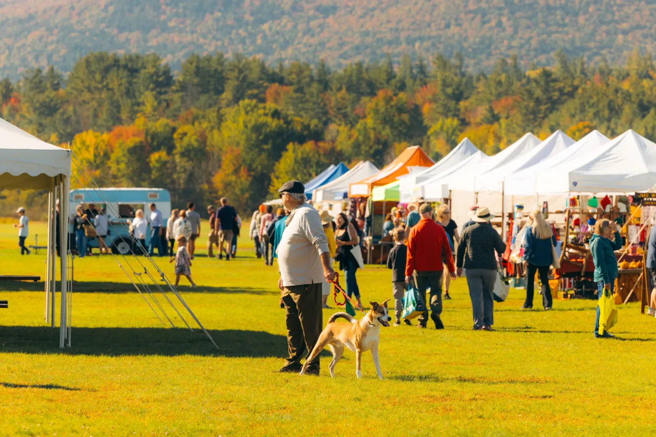A man walking his dog at a farmers market.