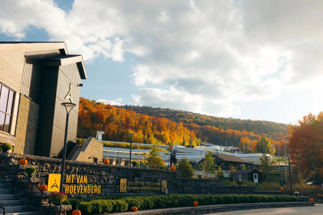 An Olympic lodge with a bobsled track behind it in the fall.