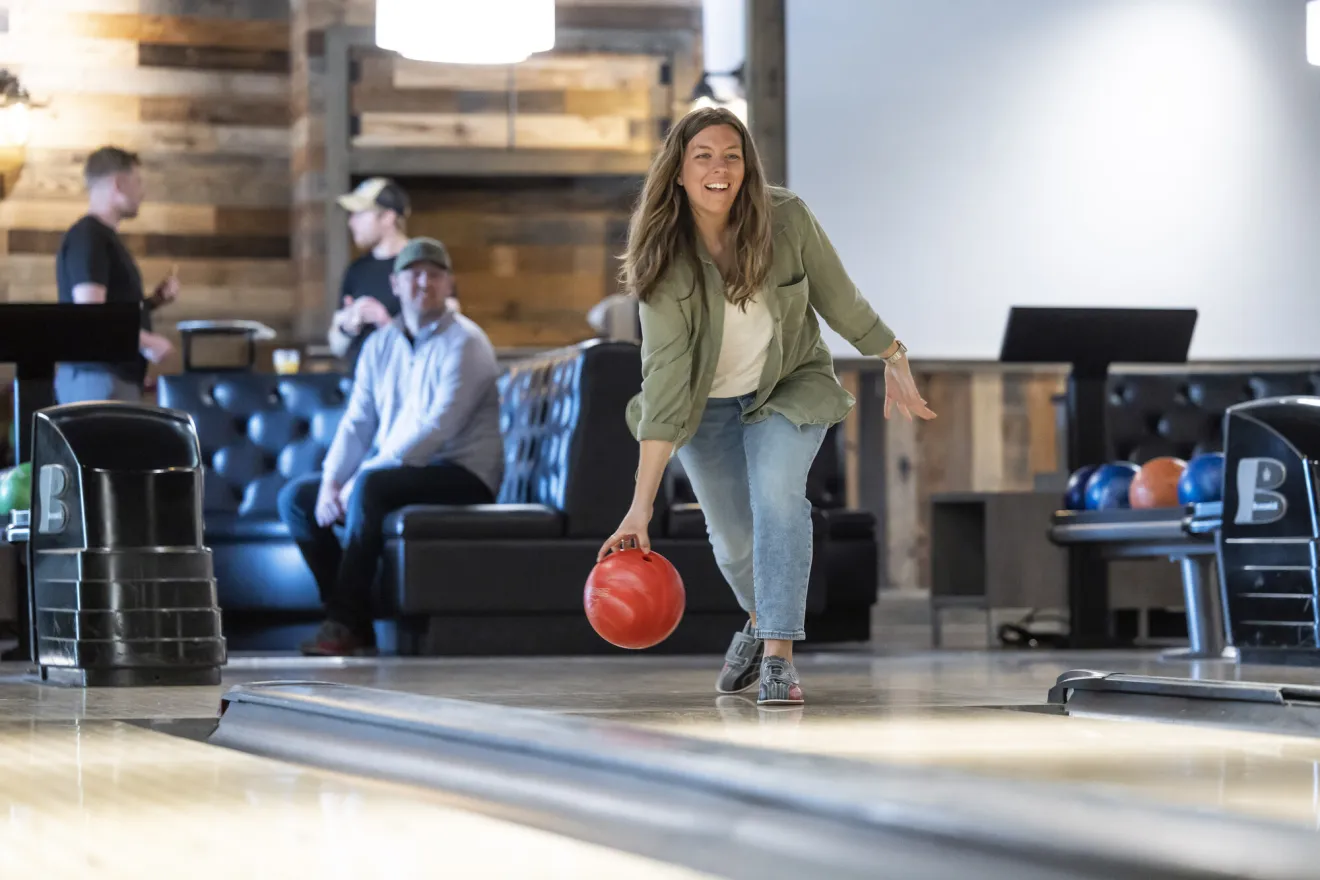 A woman throws a bowling ball. 