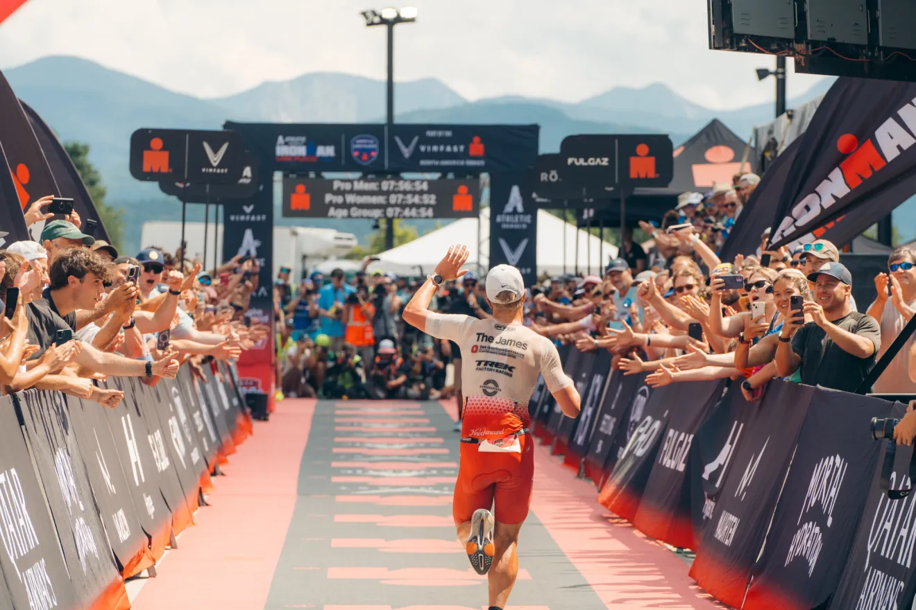 A man finishes an Ironman Race with crowds around. 