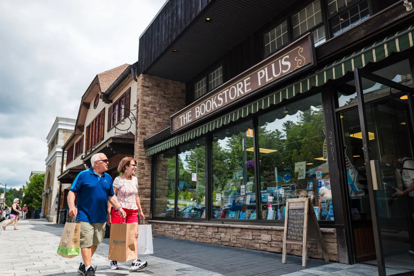 A man and woman walk in front of a book store while shopping.