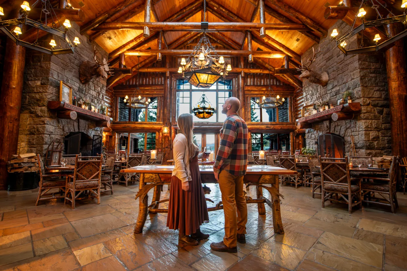 A man and woman stand in the middle of a lodge. 