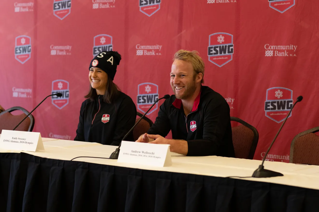 Two athletes take questions at a press conference. 