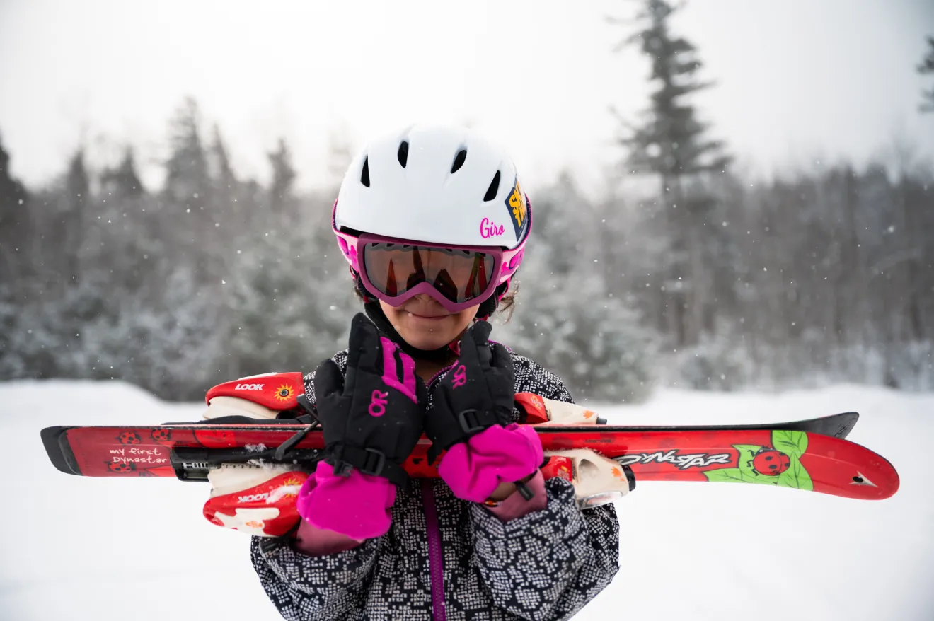 A girl carries some skis