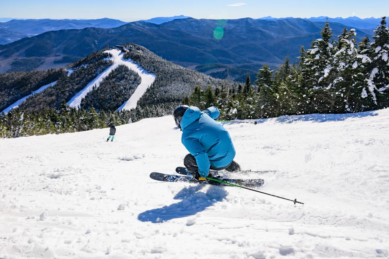 A skier in a blue jacket skis down a mountain. 