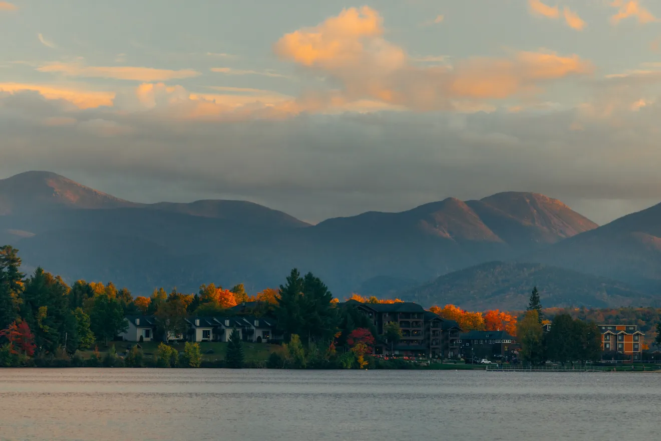 A row of condos rest on  the shore of a lake in fall.