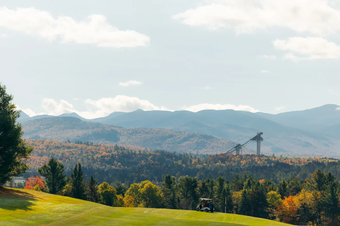 Green golf courses with fall foliage and the Olympic Ski Jumps in the backgrounds.