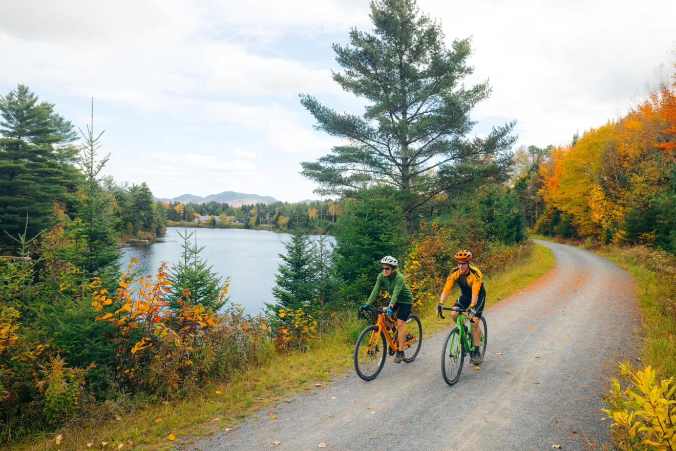 Two people biking on the Adirondack Rail Trail in the fall. 