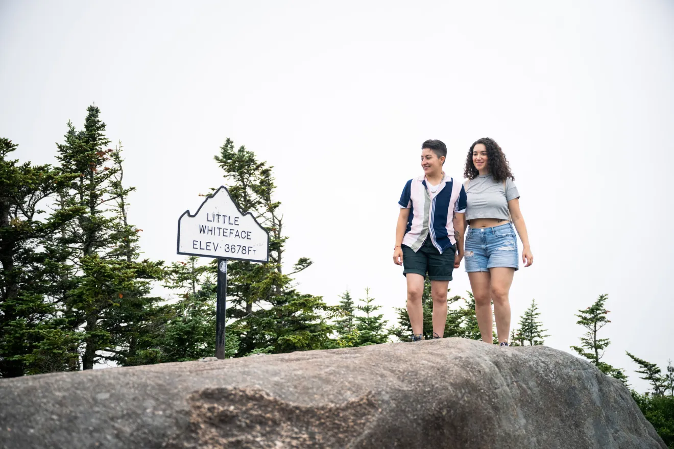 Two women walk on a mountain top in summer.