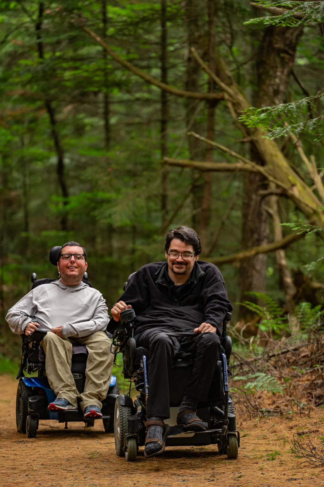 Two men on motorized wheelchairs on a path in the Adirondacks