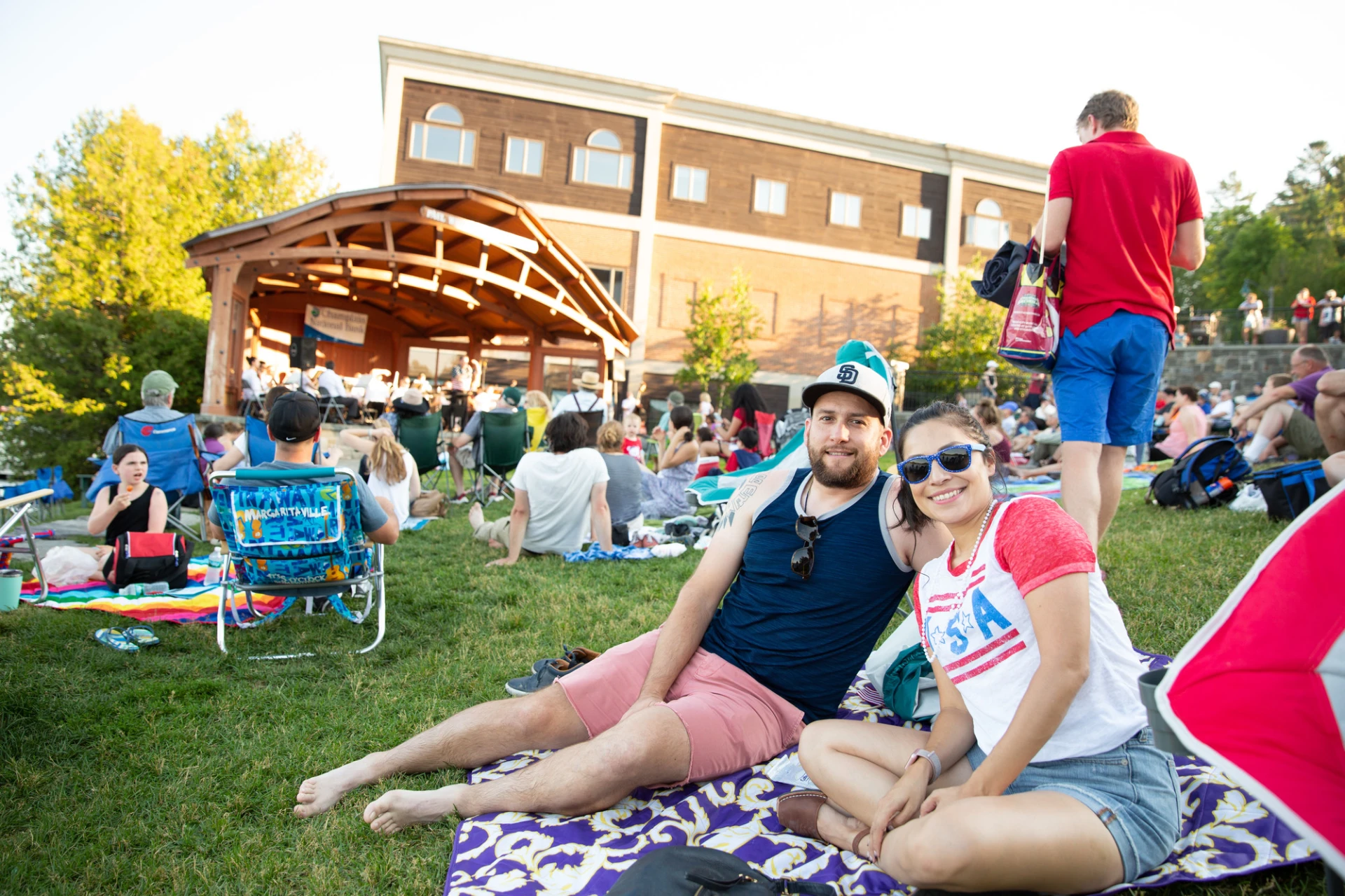 A couple lounges on a blanket in Mid's Park wearing red white and blue
