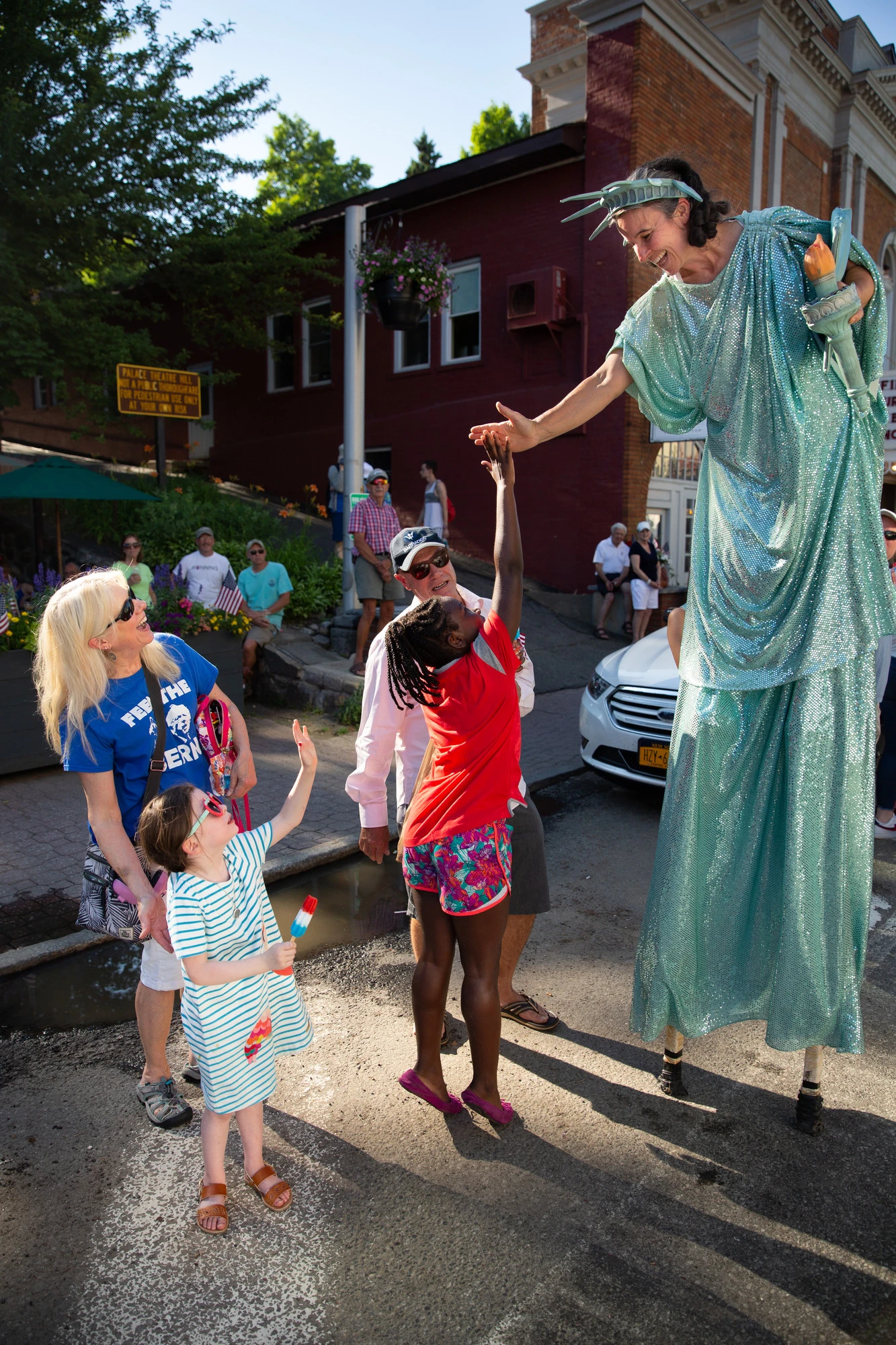 Girl reaches up the give a high five to a women dressed as the Statue of Liberty in the Lake Placid July 4th Parade