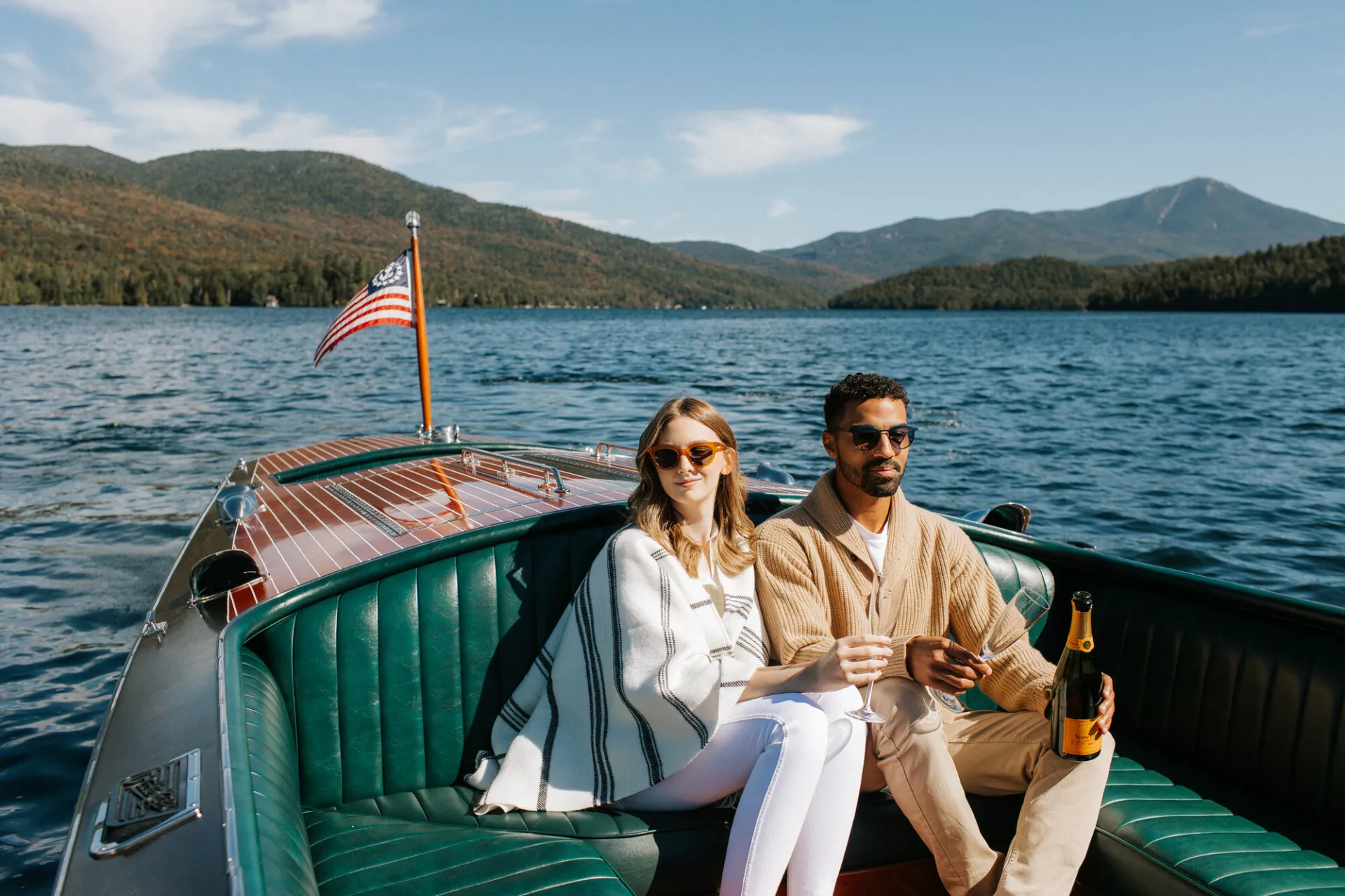 A man and a woman ride in a Chris Craft boat.