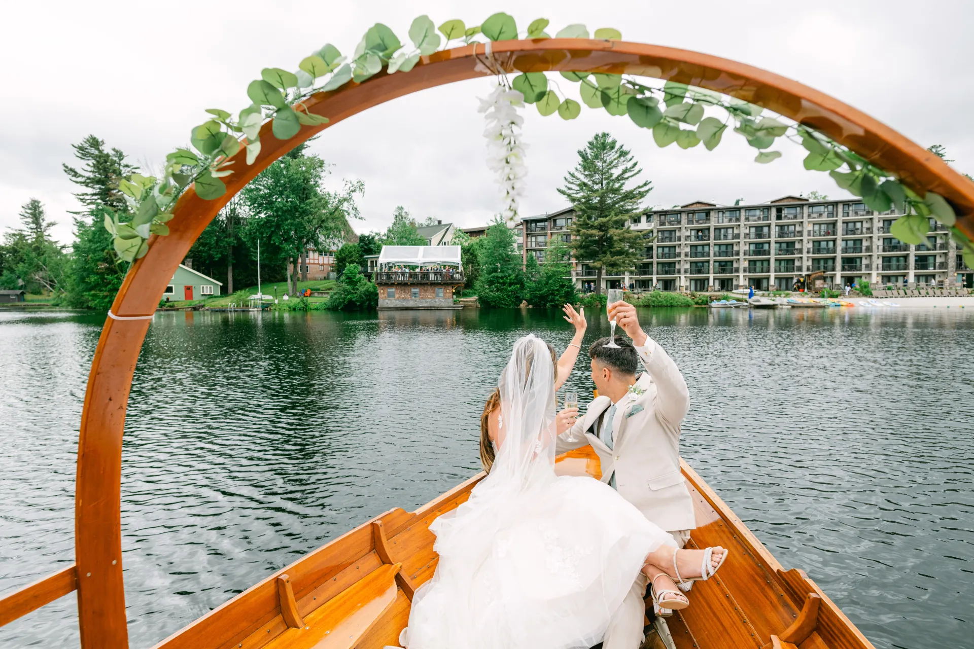 A bride and groom wave at their wedding party from the gondola on Mirror Lake from Golden Arrow.