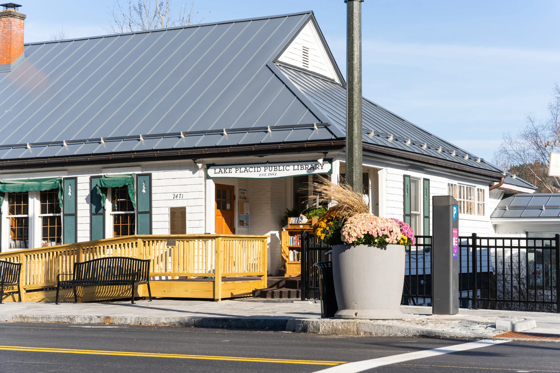 Exterior of the public library from the middle of Main Street showing the ramp, bench and community flower pots