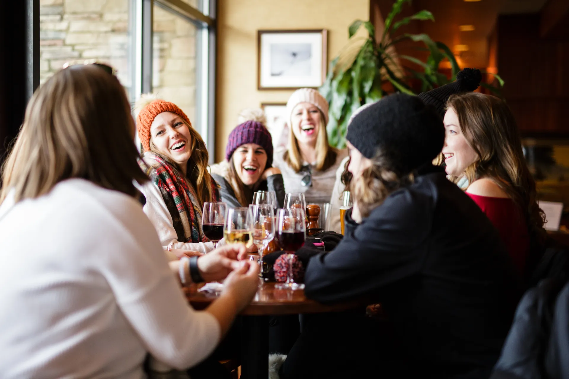 Group of women at dining table in cold weather clothing talking and laughing