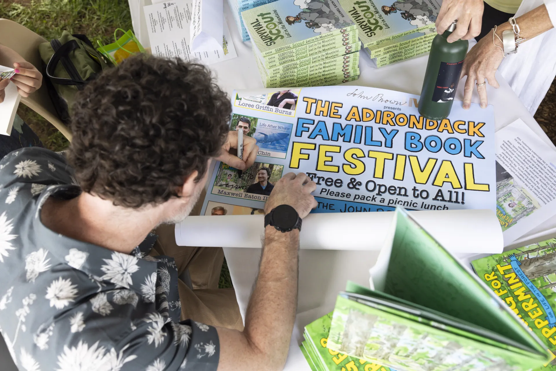 View from above as author signs Adirondack Family Book Festival poster
