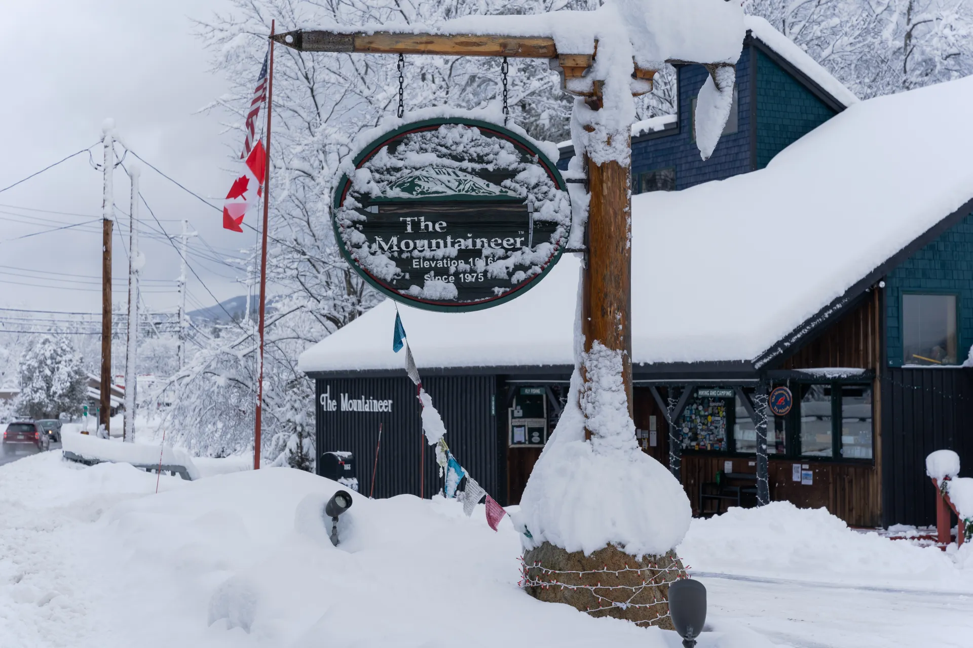 The Mountaineer's ice axe sign covered in snow, in front of the main shop building