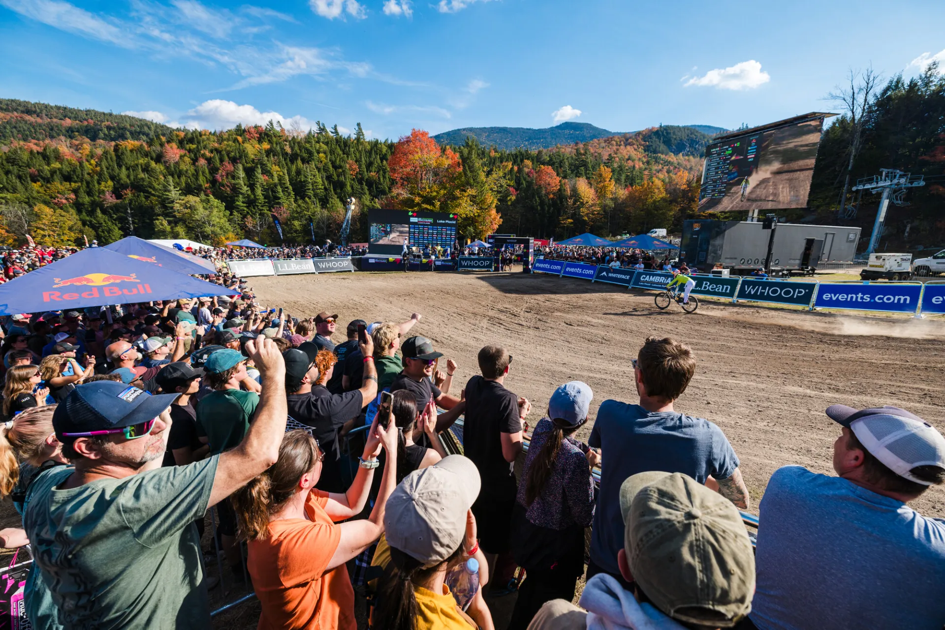 Crowd looks on as downhill mountain bike races enter finish line corral at Whiteface during UCI MTB Downhill World Cup race