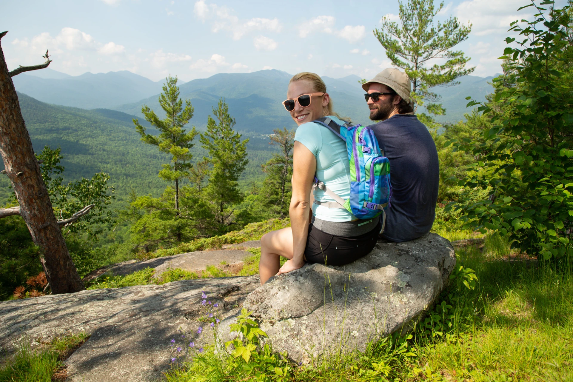 Two hikers sitting at the summit of a summer hike.