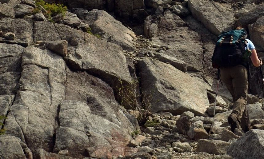 A hiker ascending a steep rocky trail