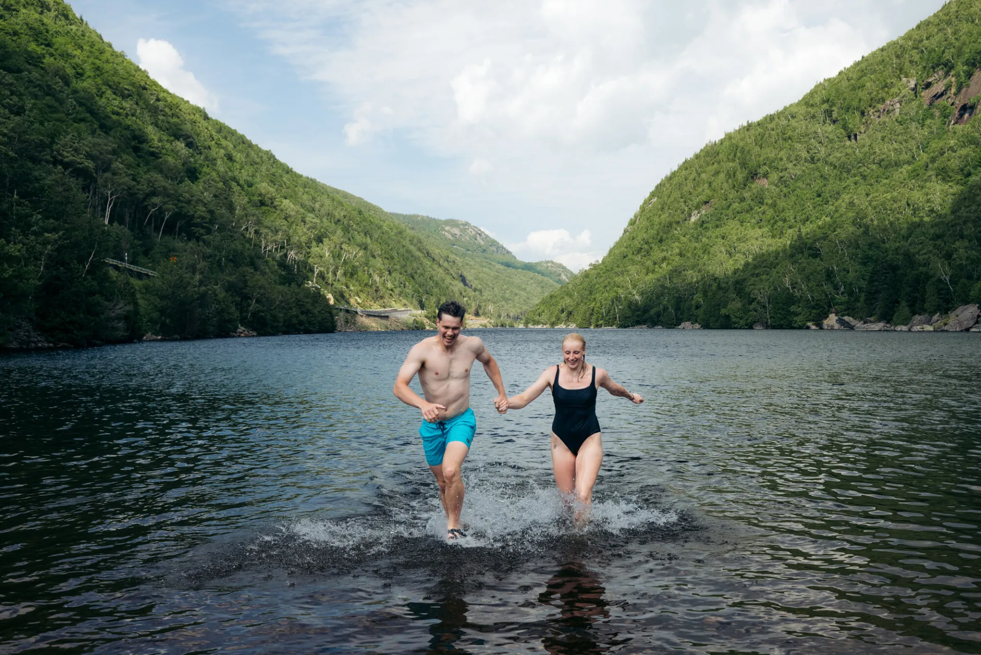 A man and woman run out of a lake. 