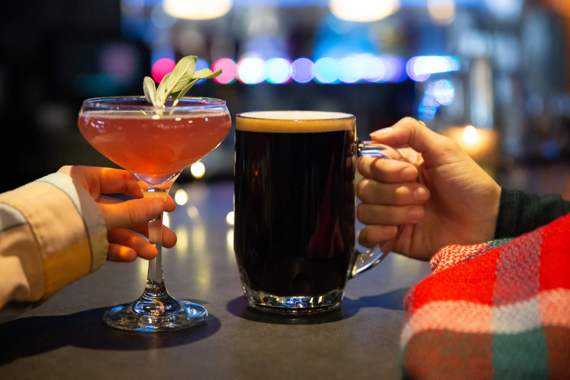Hands holding a cocktail and beer