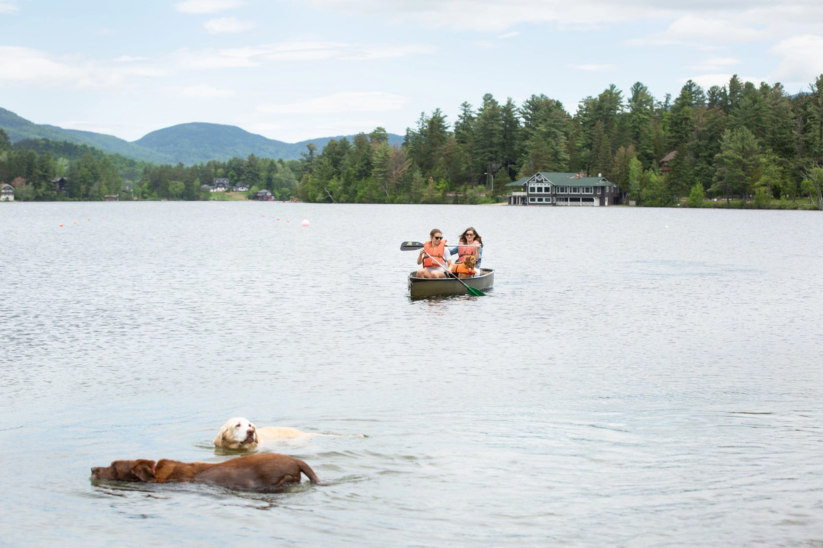 People canoe in a tandem green boat on the lake.