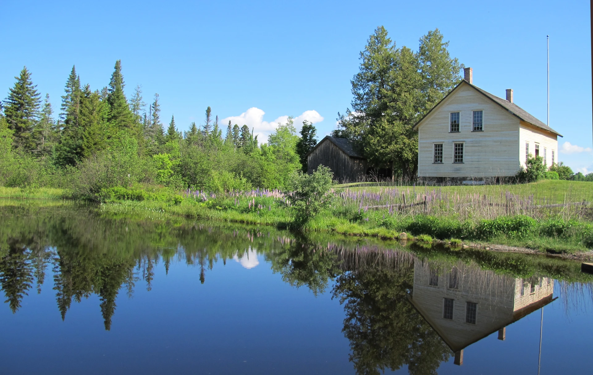 A small historic home next to a pond